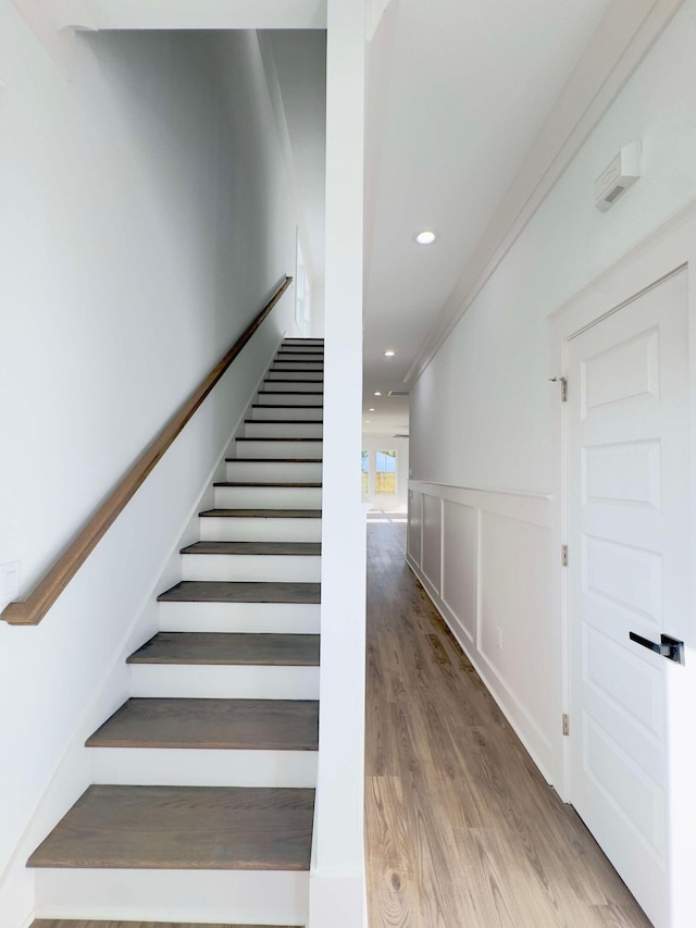 stairs with crown molding and wood-type flooring