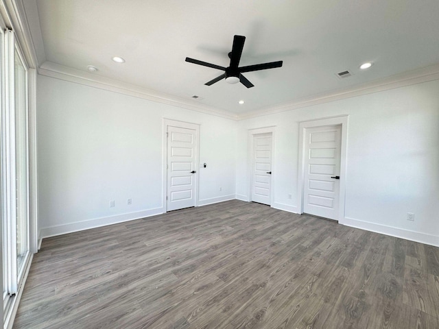 unfurnished bedroom with ceiling fan, dark hardwood / wood-style flooring, ornamental molding, and multiple closets