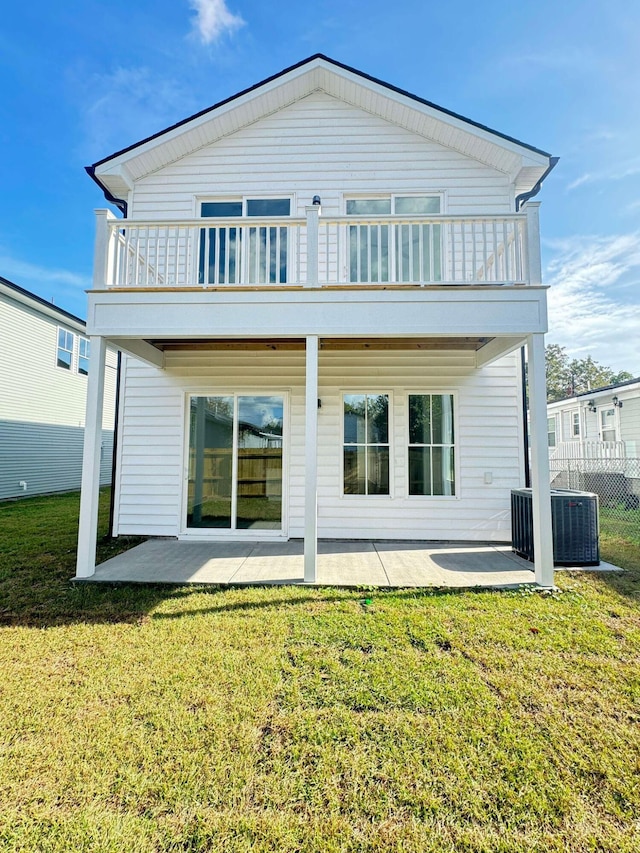 rear view of property featuring a lawn, a patio area, a balcony, and cooling unit