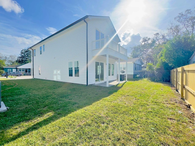 rear view of property featuring a balcony, a patio area, and a lawn