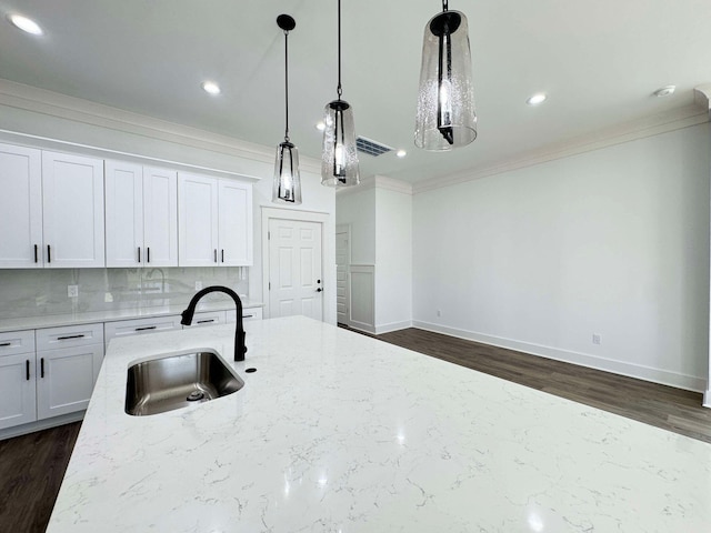 kitchen with white cabinetry, sink, dark wood-type flooring, light stone counters, and decorative light fixtures