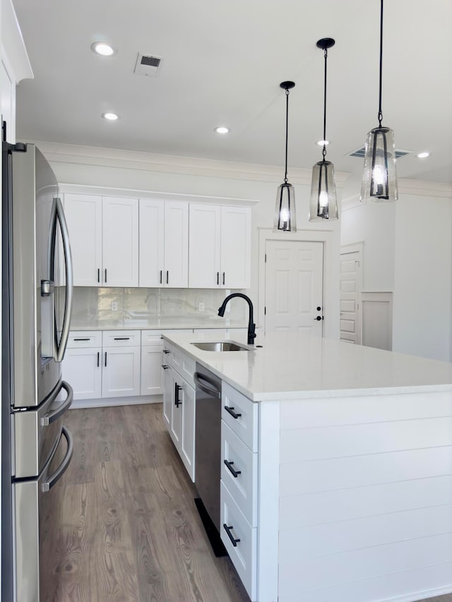 kitchen featuring stainless steel appliances, sink, decorative light fixtures, a center island with sink, and white cabinetry