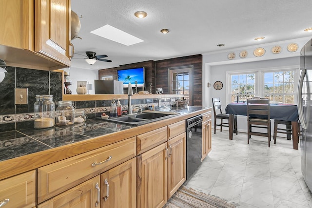 kitchen with black dishwasher, a skylight, stainless steel refrigerator, sink, and backsplash