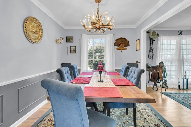 dining space featuring crown molding, light hardwood / wood-style floors, and a notable chandelier