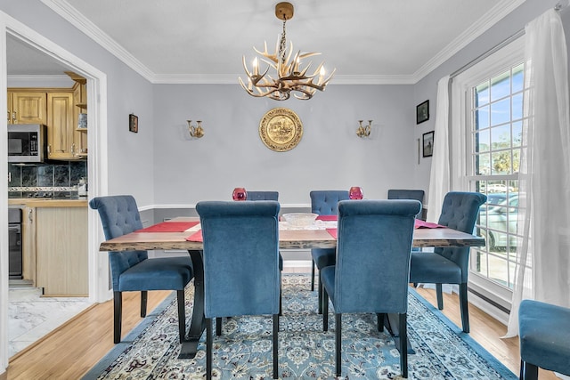 dining space with light wood-type flooring, crown molding, and an inviting chandelier