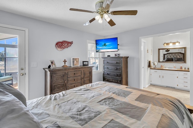 bedroom with ceiling fan, connected bathroom, access to outside, and a textured ceiling