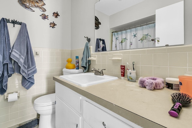 bathroom with vanity, toilet, and tile walls