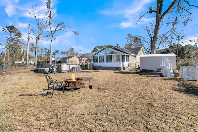 rear view of house with a sunroom and an outdoor fire pit