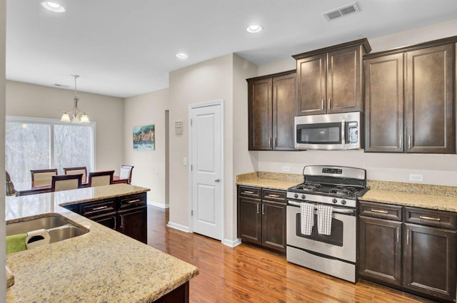 kitchen featuring dark brown cabinetry, recessed lighting, stainless steel appliances, visible vents, and light wood finished floors