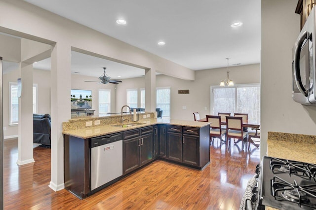 kitchen featuring light stone countertops, light wood-style floors, stainless steel appliances, and a sink