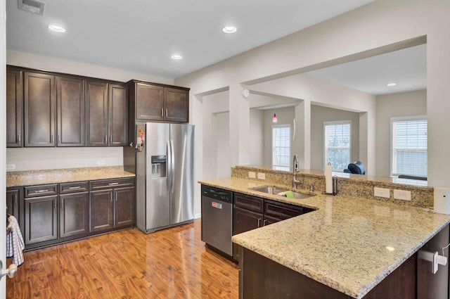 kitchen with stainless steel appliances, a sink, visible vents, light wood-style floors, and dark brown cabinets