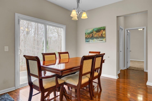 dining space featuring a chandelier, wood finished floors, and baseboards