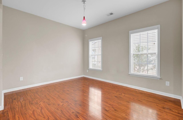 unfurnished room with visible vents, baseboards, and wood finished floors