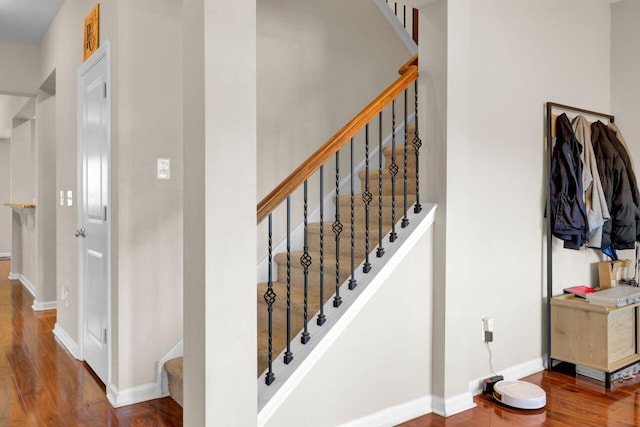 staircase featuring baseboards and wood finished floors