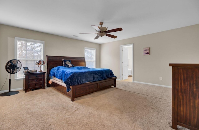 carpeted bedroom featuring a ceiling fan, visible vents, ensuite bath, and baseboards