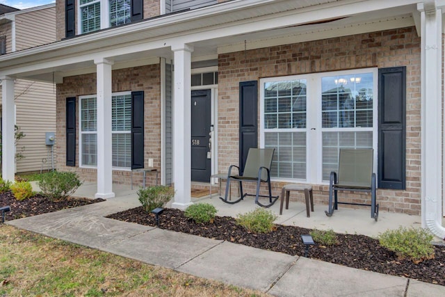 doorway to property with covered porch and brick siding