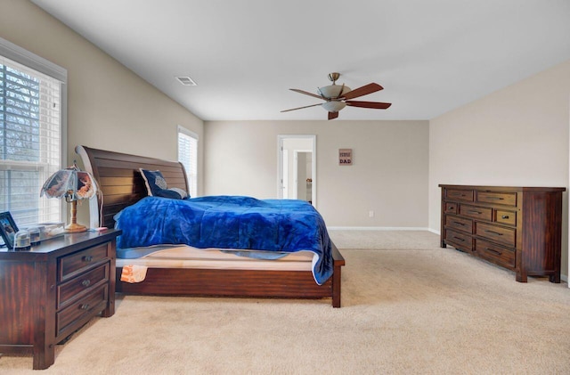 bedroom with light carpet, ceiling fan, visible vents, and baseboards