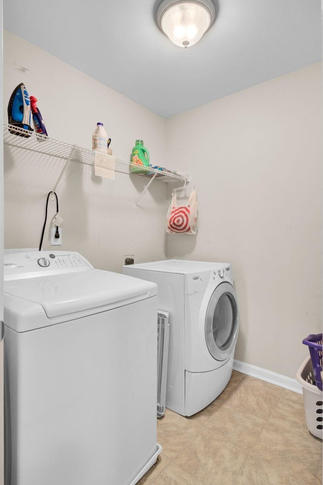 washroom with laundry area, washing machine and dryer, and baseboards