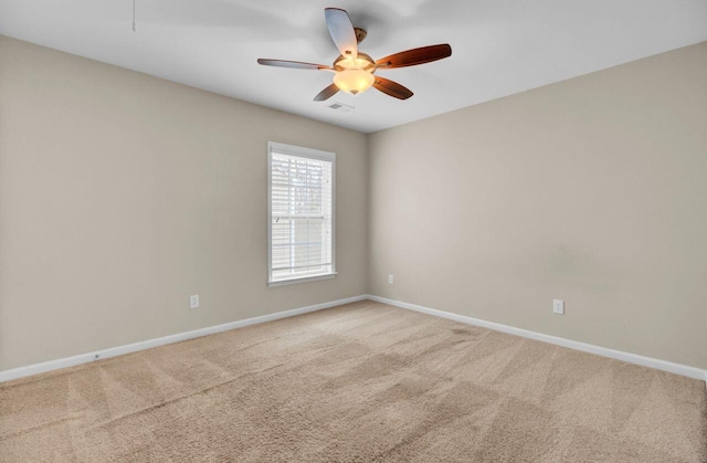 carpeted empty room featuring ceiling fan, visible vents, and baseboards