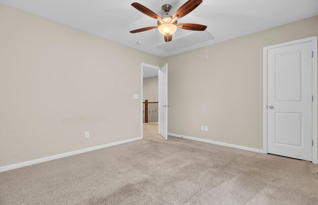 carpeted empty room with attic access and baseboards