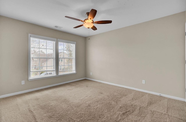 empty room with carpet floors, visible vents, baseboards, and a ceiling fan