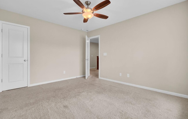 carpeted empty room featuring ceiling fan and baseboards