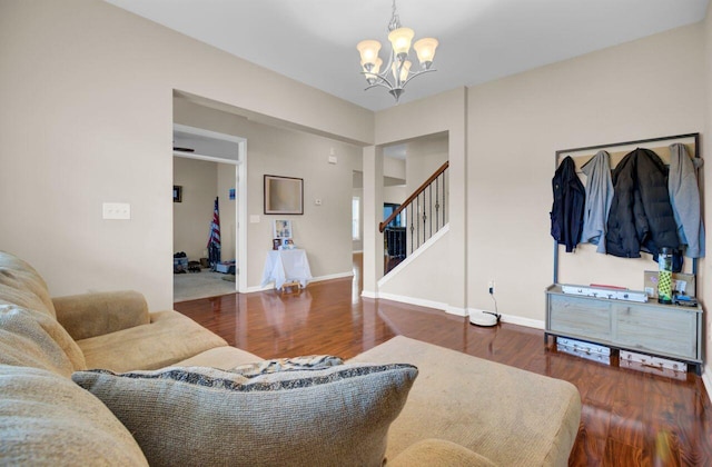 living area with baseboards, stairway, an inviting chandelier, and wood finished floors