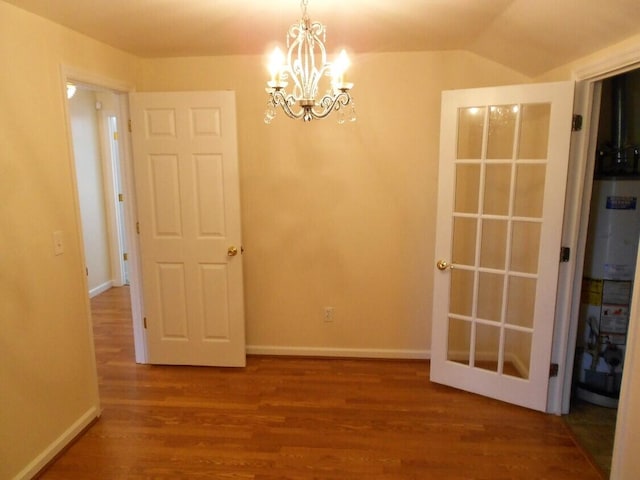 unfurnished room with wood-type flooring, gas water heater, vaulted ceiling, and an inviting chandelier