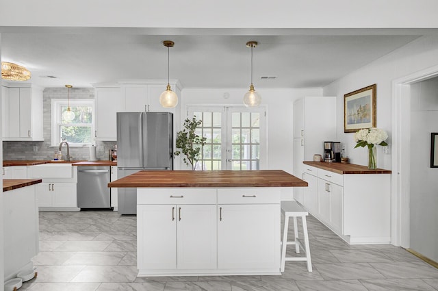 1032 Windward Rd, Charleston, SC 29412 - kitchen featuring butcher block counters, appliances with stainless steel finishes, light marble finish flooring, decorative backsplash, and a kitchen island