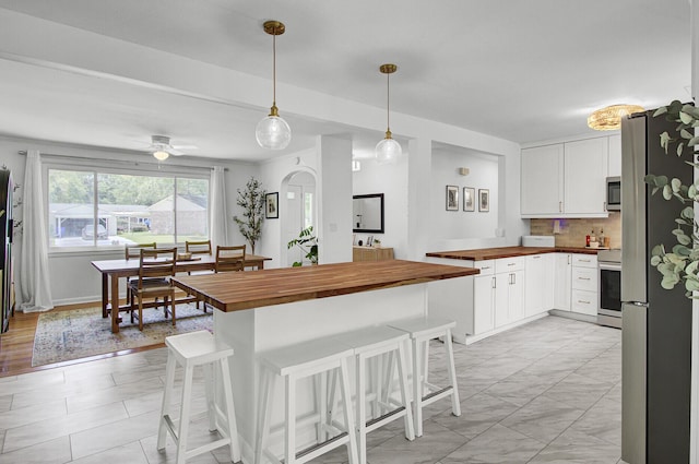 1032 Windward Rd, Charleston, SC 29412 - kitchen featuring wood counters, stainless steel appliances, a breakfast bar, tasteful backsplash, and white cabinetry
