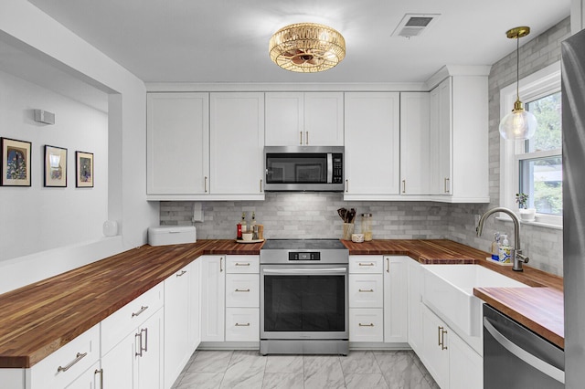 1032 Windward Rd, Charleston, SC 29412 - kitchen with appliances with stainless steel finishes, butcher block countertops, light marble finish floors, and tasteful backsplash