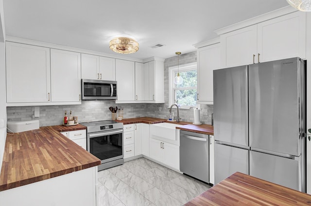 1032 Windward Rd, Charleston, SC 29412 - kitchen with butcher block counters, appliances with stainless steel finishes, light marble finish floors, decorative backsplash, and white cabinets