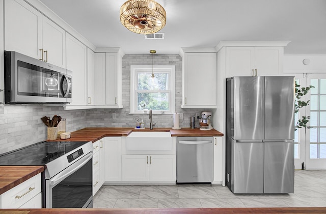 1032 Windward Rd, Charleston, SC 29412 - kitchen featuring appliances with stainless steel finishes, butcher block countertops, light marble finish flooring, decorative backsplash, and white cabinets