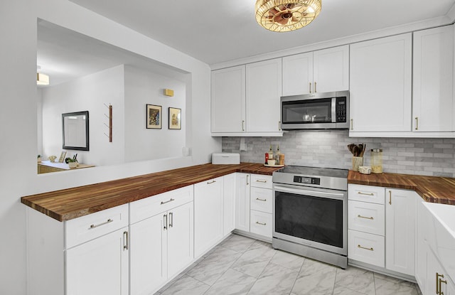 1032 Windward Rd, Charleston, SC 29412 - kitchen featuring butcher block counters, appliances with stainless steel finishes, light marble finish floors, a peninsula, and backsplash