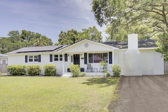 1032 Windward Rd, Charleston, SC 29412 - ranch-style house featuring a chimney, a porch, a front yard, and roof mounted solar panels