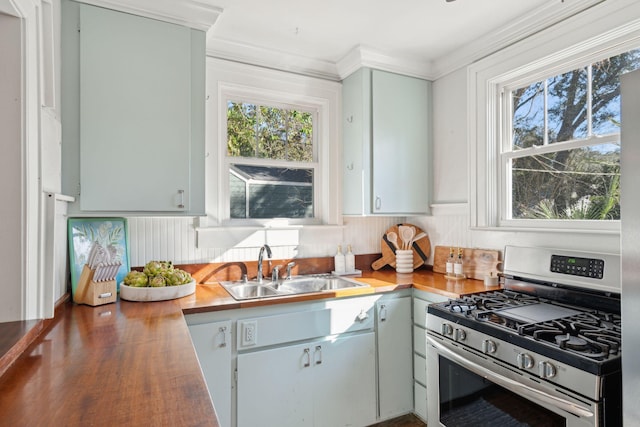 kitchen with sink, wood counters, stainless steel gas range oven, ornamental molding, and hardwood / wood-style flooring