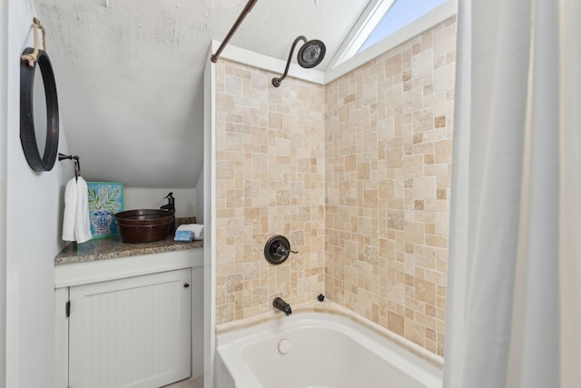 bathroom featuring vaulted ceiling, vanity, and tiled shower / bath combo