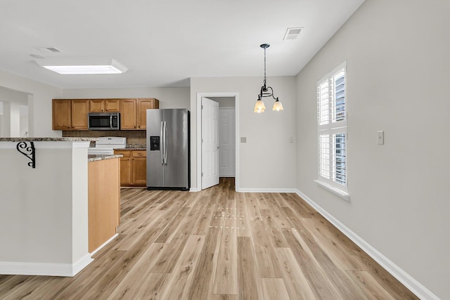 kitchen with stainless steel appliances, visible vents, light wood-style flooring, light stone countertops, and baseboards