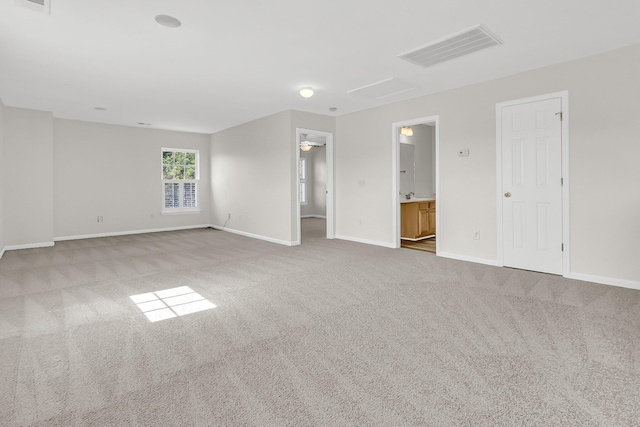 empty room with carpet, visible vents, and baseboards
