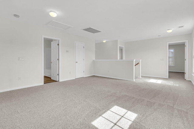 empty room with visible vents, carpet, attic access, and baseboards