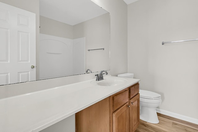 bathroom featuring wood finished floors, vanity, toilet, and baseboards