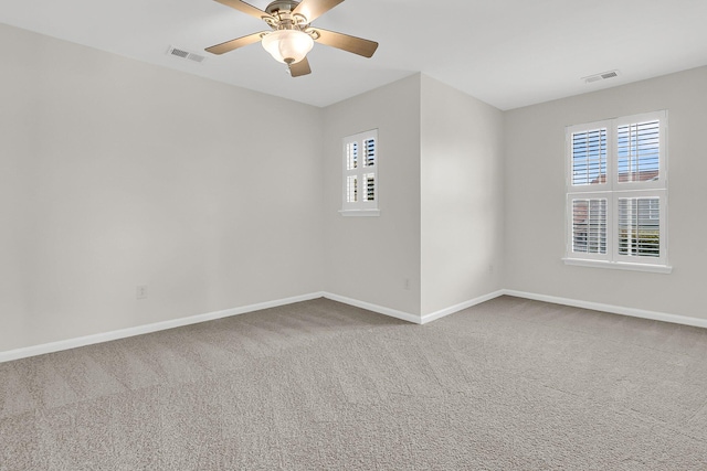 spare room with carpet flooring, visible vents, and baseboards