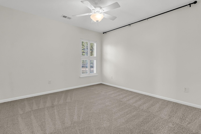 empty room with carpet floors, baseboards, visible vents, and a ceiling fan