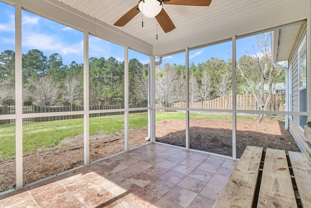 unfurnished sunroom with a view of trees and a ceiling fan