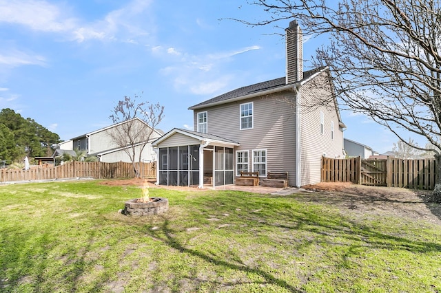 rear view of house with a fire pit, a sunroom, a fenced backyard, a chimney, and a yard