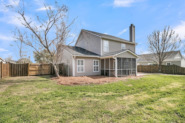rear view of house featuring a yard, a chimney, a fenced backyard, and a sunroom