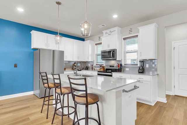 kitchen featuring an island with sink, sink, light hardwood / wood-style flooring, and appliances with stainless steel finishes