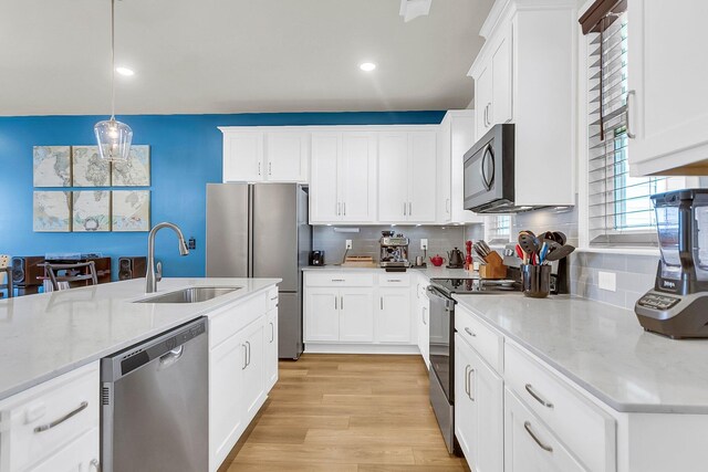 kitchen featuring sink, white cabinetry, appliances with stainless steel finishes, and decorative light fixtures