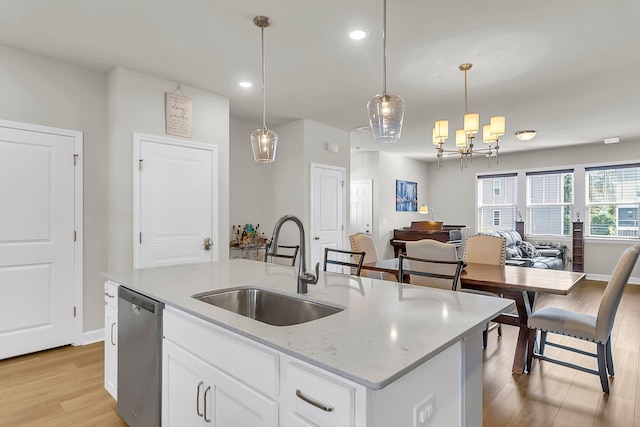 kitchen featuring light hardwood / wood-style floors, white cabinets, an island with sink, stainless steel dishwasher, and decorative light fixtures