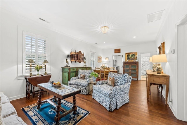 living room featuring baseboards, crown molding, visible vents, and wood finished floors